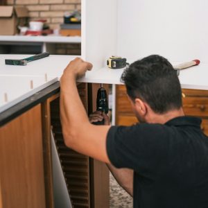 Worker using a drill to build a kitchen furniture